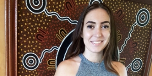 Young Aboriginal woman in front of Aboriginal painting